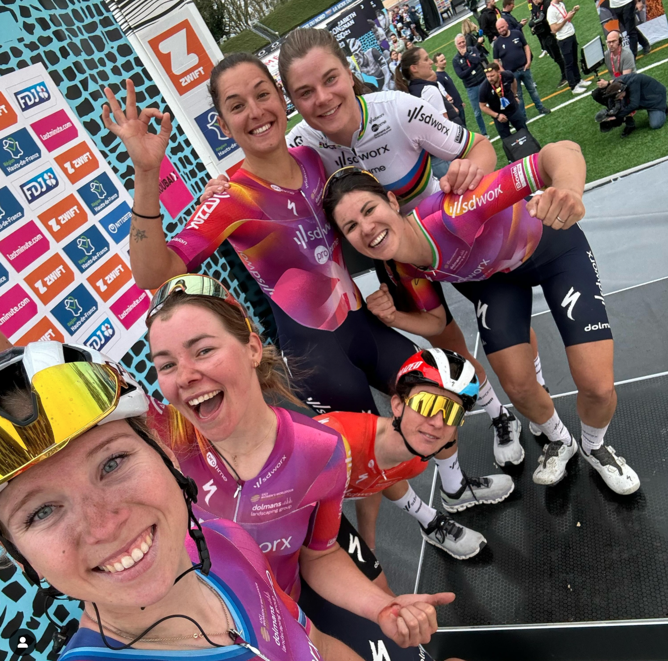 A team of women pose on a podium after winning a bike race